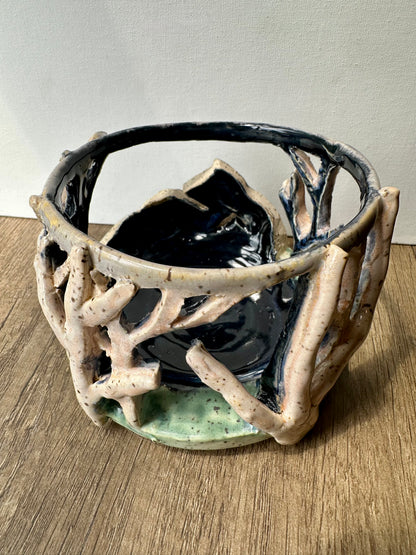 Round ceramic candle surround with mountain and birch trees cut out.