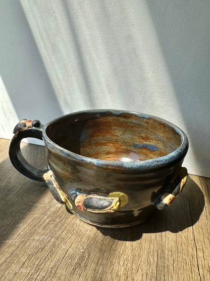 Bronze-colored mug with streaks of inky blue and sculpted fireflies.